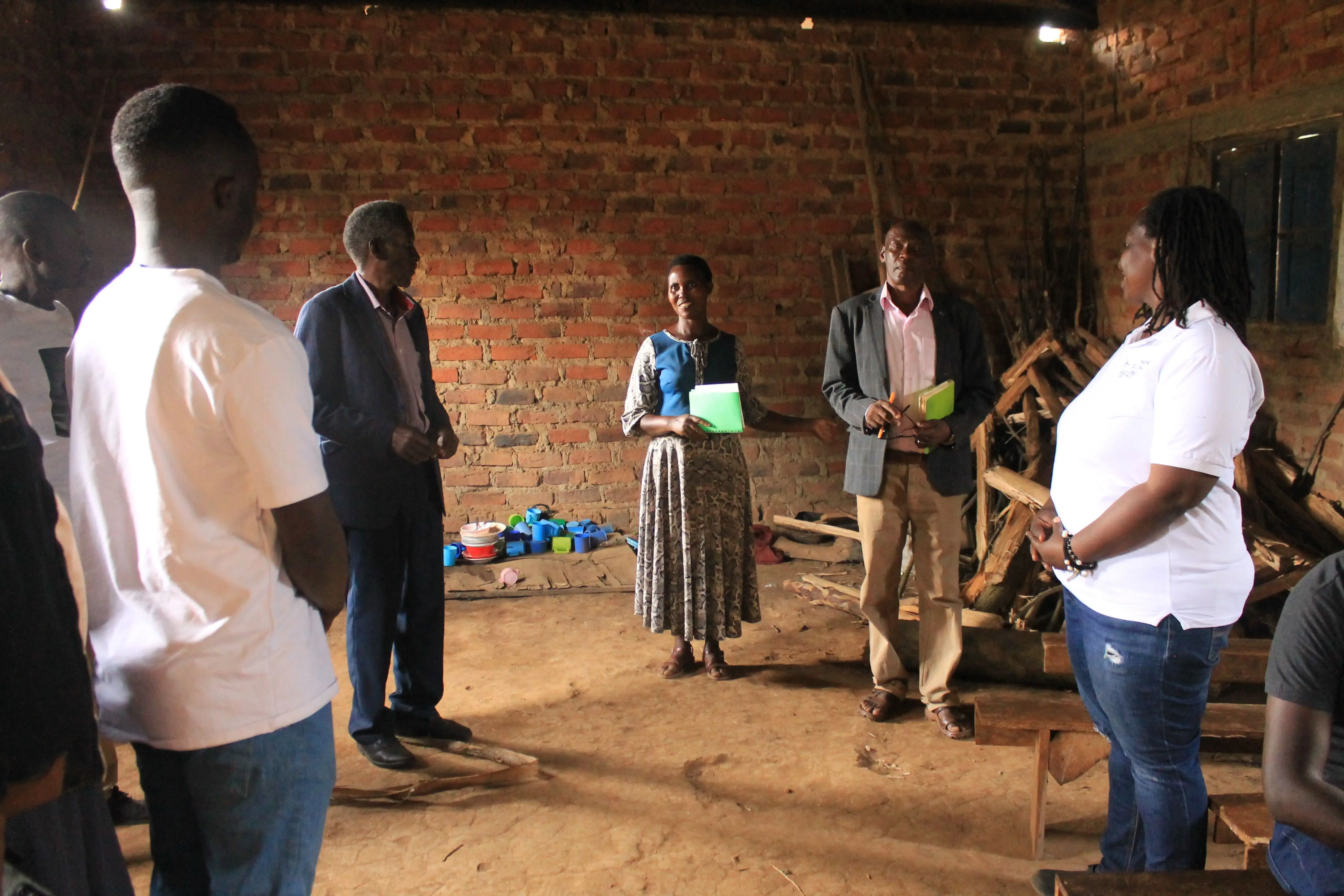 Huruma team members meeting teachers inside a brick classroom that also stores firewood
