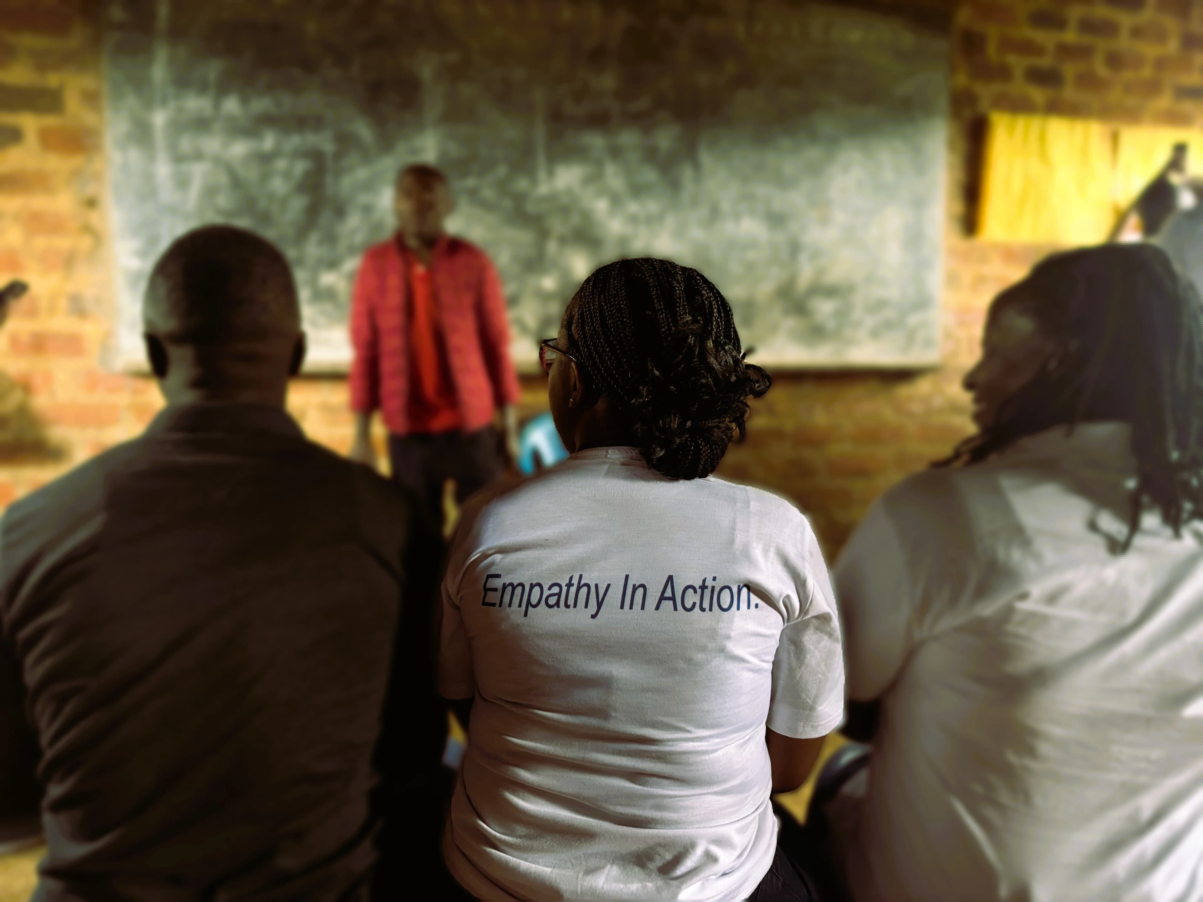 Huruma volunteers in Empathy in Action shirts watching a lesson at the chalkboard